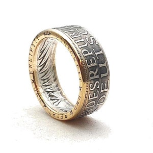 Könnte beinhalten: Ein silberner Ring mit einem goldenen Band, mit der Inschrift "Bundesrepublik Deutschland" am Rand.
