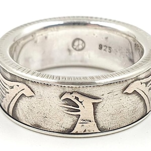 Op de afbeelding: Zilveren ring met een gedetailleerd ontwerp van twee gestileerde vogels op de band. De ring is gemarkeerd met "925" aan de binnenkant.