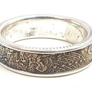 Pode incluir: Um anel de prata com uma banda dourada que apresenta um design de estrelas e uma lua crescente.