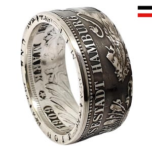 Pode incluir: Anel de prata feito com uma moeda alemã antiga. O anel tem a inscrição "Freie und Hansestadt Hamburg" e uma representação de um leão.