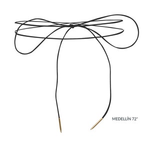 May include: Black leather choker necklace with gold-tipped ends. The necklace is tied in a bow at the back of the neck. MEDELLÍN 72" is printed on the white background.