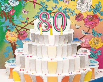 May include: A colorful 3D pop-up card with a cake design. The cake has 80 candles and says "Happy Birthday". The card is decorated with flowers, butterflies, and birds.