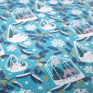 May include: Blue wrapping paper with a repeating pattern of white birdcages filled with small trees, birds, and deer. The background is a light blue with white snowflakes.