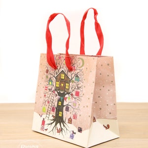 May include: A pink and white gift bag with red handles. The bag features a whimsical illustration of a tree house with a light on in the window. The tree is decorated with small houses, birds, and stars. The text "Dreamy London" is printed on the bottom of the bag.