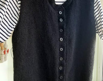 May include: Black knitted vest with a button closure. The vest has a round neckline and is sleeveless. The label on the vest reads "NEW STYLE".