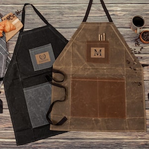May include: Two canvas aprons with pockets and adjustable straps. One apron is black with a white logo that says "Remarkable". The other apron is brown with a brown leather patch that says "MIVI".