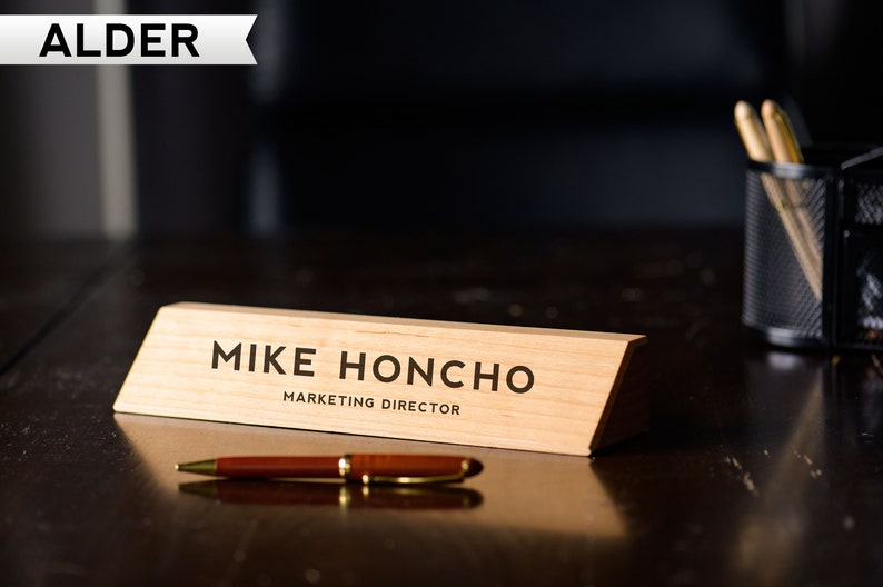 May include: A wooden desk nameplate with the text "Mike Honcho, Marketing Director" in black lettering.