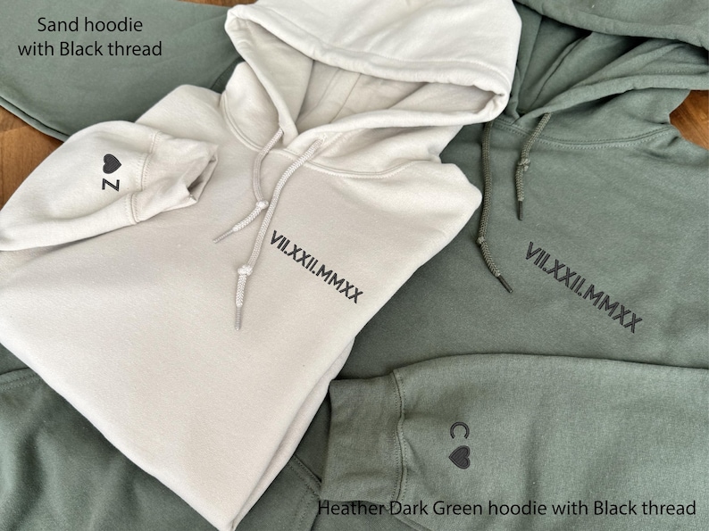 May include: Sand-colored hoodie with black thread, featuring a hood and drawstring. The sleeve displays a heart and the letter "Z". The front of the hoodie has the roman numerals "VII.XXII.MMXX". A heather dark green hoodie is also shown.