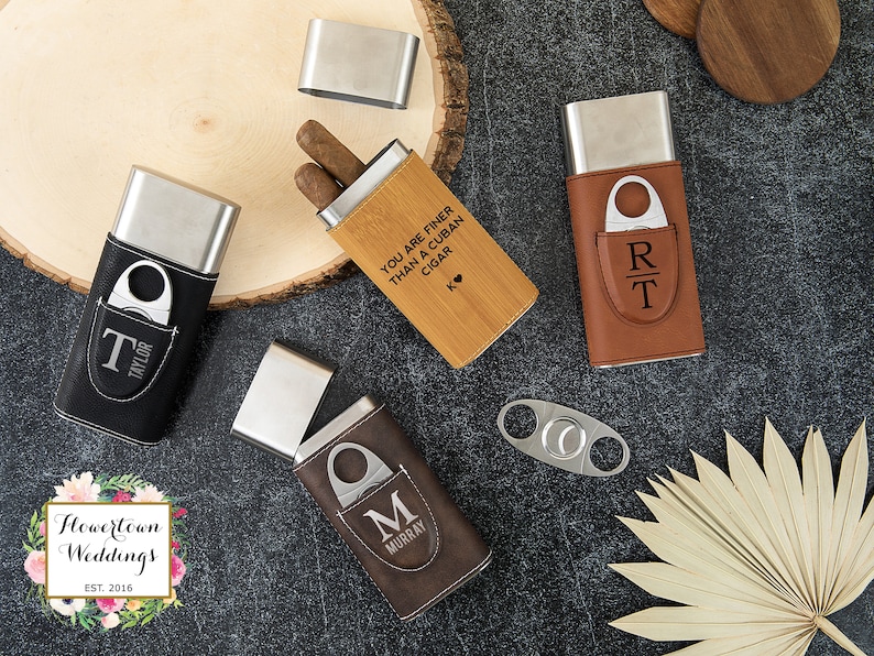 May include: Four different cigar cases with a built-in cutter. The cases are made of leather and wood and have different engravings. One case has the text "You are finer than a Cuban cigar" engraved on it. Another case has the initials "RT" engraved on it. The third case has the initial "M" engraved on it. The fourth case has the initial "T" engraved on it.
