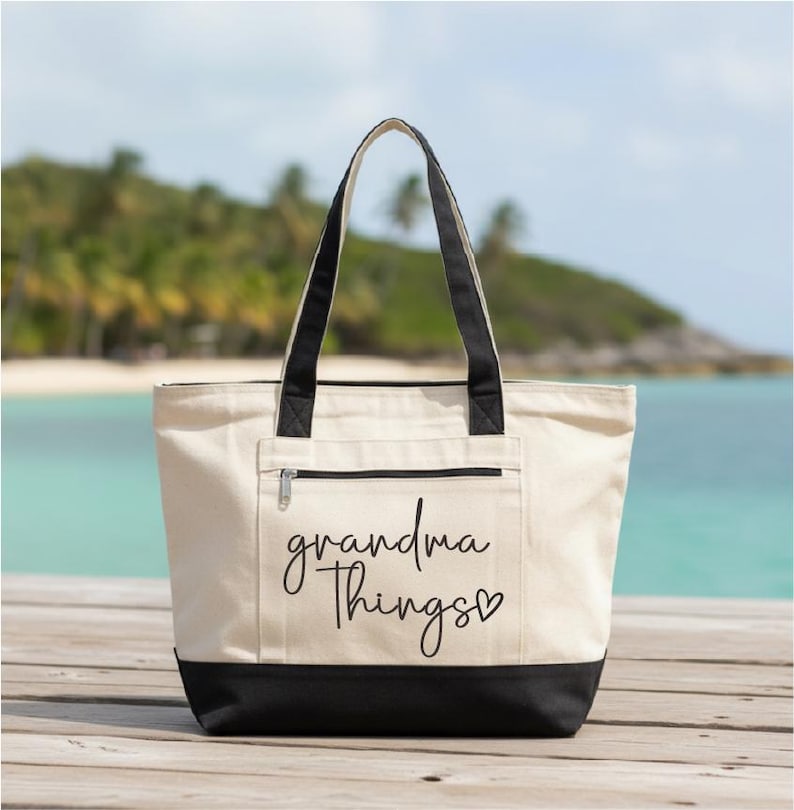 Op de afbeelding: Een cr&egrave;mekleurige canvas draagtas met zwarte handvatten en bodem. De tas heeft een ritsvak aan de voorkant en de tekst "grandma things" in cursief met een hartje.