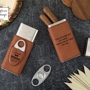 May include: Two brown leather cigar cases with silver metal inserts. One case has the text "You stood by my side... Now have one on me..." engraved on the front. The other case has the text "Joseph Groomman 0427.24" engraved on the front. A silver cigar cutter is also pictured.