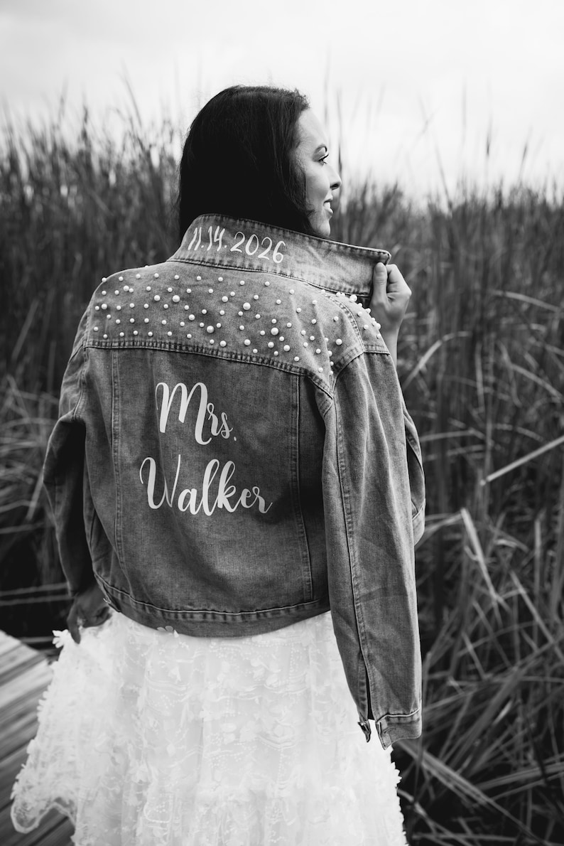 May include: A black and white photo of a person wearing a denim jacket with pearl embellishments. The jacket has the text "Mrs. Walker" and the date "11.14.2026" written on the back.