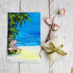 Könnte beinhalten: Ein Gemälde, das eine tropische Strandszene mit einer Palme, blauem Wasser und weißem Sand zeigt. Das Gemälde ist in einem lebendigen Stil mit leuchtenden Farben gehalten.