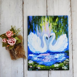 May include: A painting of two white swans with their necks intertwined, set against a backdrop of a blue lake with green foliage and lily pads. The swans are painted in a realistic style with visible brushstrokes.