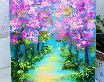 May include: A painting on canvas depicting a forest path lined with trees in bloom. The trees have pink flowers and green leaves. The path is illuminated by a bright yellow light. The painting is signed "milaccc" in the bottom right corner.