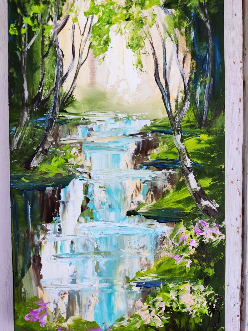 Op de afbeelding: Een schilderij van een waterval in een bos. Het water is helderblauw en wit, en de bomen zijn groen. Op de voorgrond zijn roze bloemen te zien.