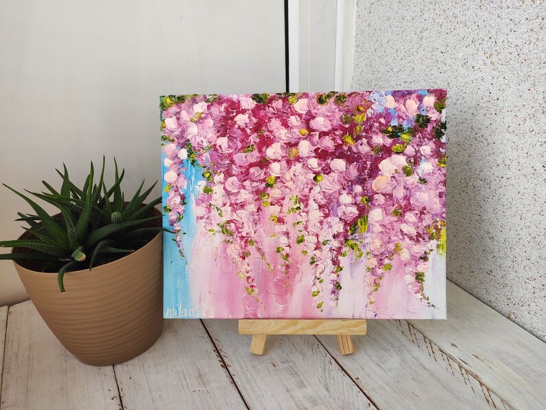 K&ouml;nnte beinhalten: Ein Gem&auml;lde auf Leinwand mit rosa und wei&szlig;en Blumen und gr&uuml;nen Bl&auml;ttern. Das Gem&auml;lde steht auf einem kleinen Staffelei.