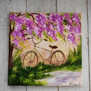 May include: A painting of a bicycle parked under a tree with purple flowers. The bicycle is brown with a brown seat and black tires. The background is a light yellow with green grass and a white path.
