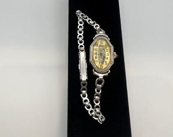 This is a white gold Benrus Art Deco ladies' wristwatch featuring a sapphire cabochon.
