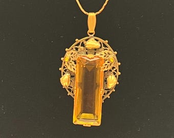 Vintage Coro pendant with amber-colored glass and ornate metalwork.