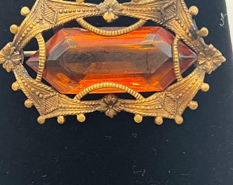 This is a vintage amber glass filigree brooch.