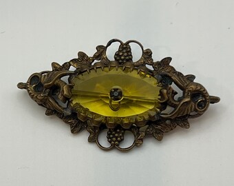 This is an antique brooch featuring a yellow stone and floral design.