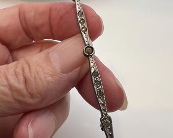 This is an Art Deco era bar brooch featuring set stones.