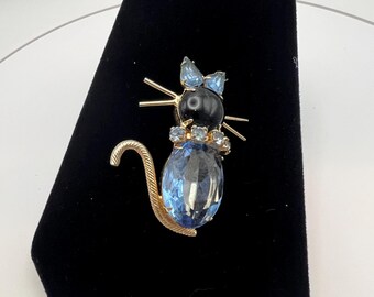 A vintage gold-toned metal cat brooch with blue gemstone and rhinestones.