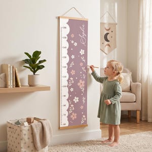 May include: A vertical wall-mounted growth chart featuring a mauve background with a white floral pattern and a scalloped edge. The chart displays measurements from 60 to 160 centimeters and includes the name Sophia in white script lettering.