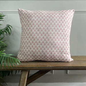 May include: A pink and white patterned cushion with a leaf design. The cushion is sitting on a wooden bench.
