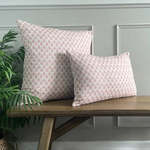 May include: Two pink and white patterned throw cushions on a wooden bench. The cushions have a floral design.