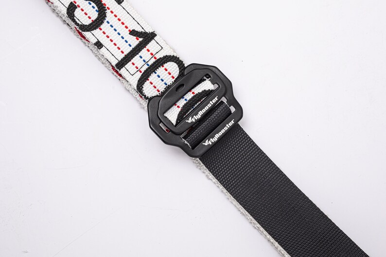 May include: A white and black patterned belt with a black buckle. The buckle has the word "Flybooster" printed on it.