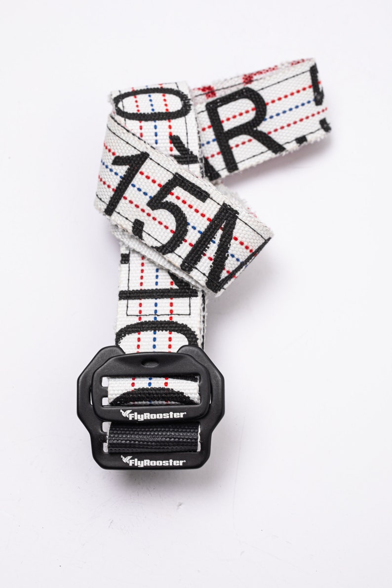 May include: White and black patterned belt with a black buckle. The buckle has the text "FlyRooster" printed on it.