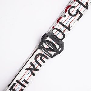 May include: White belt with black text and red and blue stitching. The belt has a black buckle with the word "FlyRooster" printed on it.