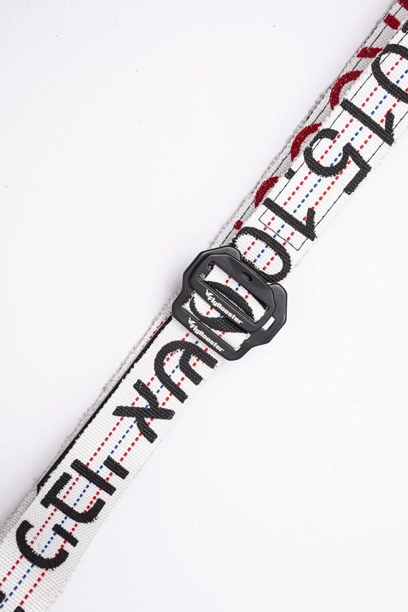 May include: White belt with black text and red and blue stitching. The belt has a black buckle with the word "FlyRooster" printed on it.