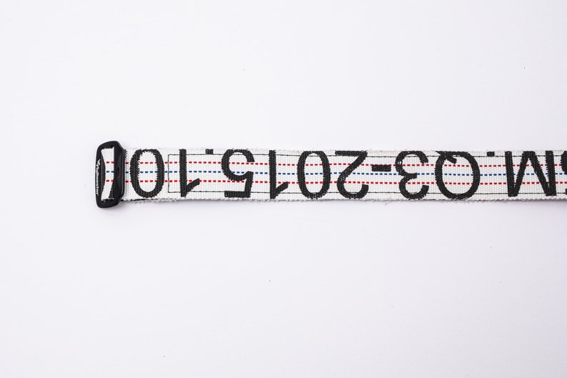 May include: White belt with black text that reads "W-30-2019-10". The belt has red and blue stripes.