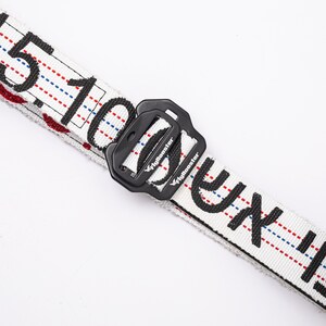 May include: White belt with black text that reads "C.F.T.I. 100.15" and a black plastic buckle with the text "Flymonster" on it.