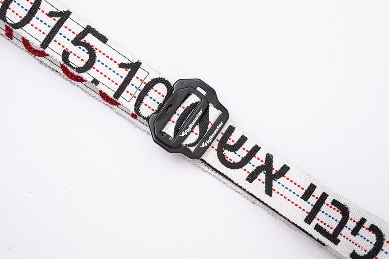 May include: White belt with black text that reads "C.F.T.I. 100.15" and a black plastic buckle with the text "Flymonster" on it.