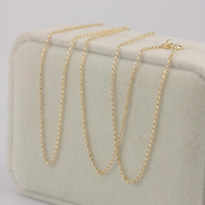 K&ouml;nnte beinhalten: Drei zarte Goldhalsketten, pr&auml;sentiert auf einer weichen, cremefarbenen Oberfl&auml;che. Jede Kette hat ein einzigartiges Design mit unterschiedlichen Texturen und Gliedermustern. Die Halsketten sind in einer ordentlichen Anordnung pr&auml;sentiert, die ihre individuellen Stile zeigt.