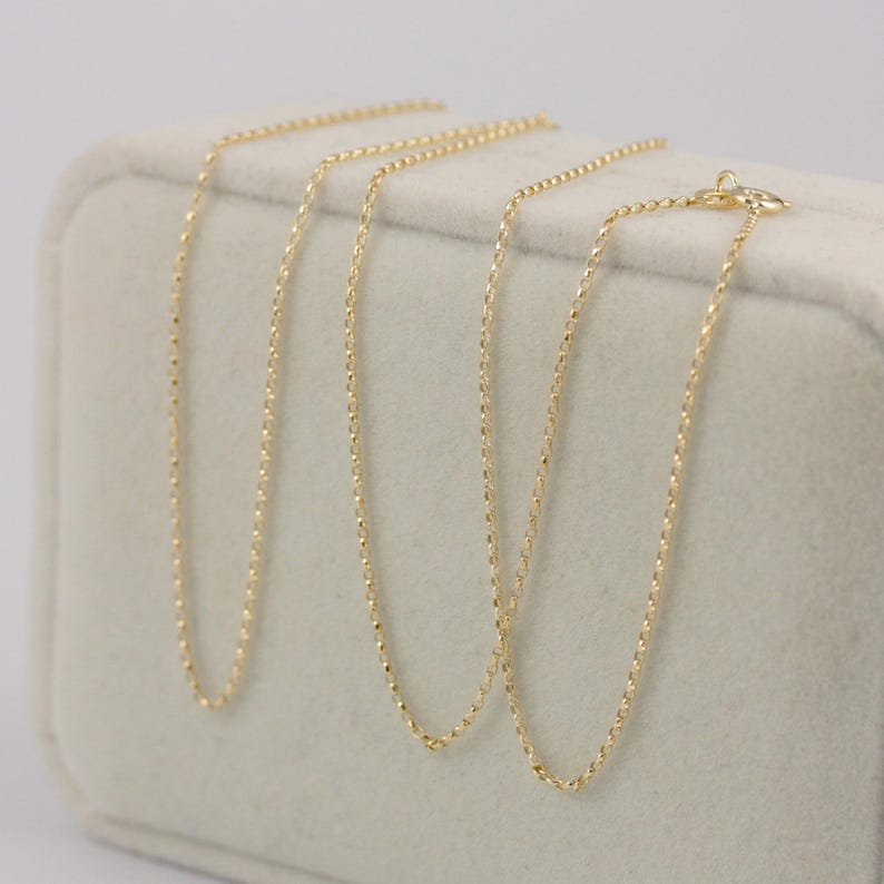 K&ouml;nnte beinhalten: Drei zarte Goldhalsketten, pr&auml;sentiert auf einer weichen, cremefarbenen Oberfl&auml;che. Jede Kette hat ein einzigartiges Design mit unterschiedlichen Texturen und Gliedermustern. Die Halsketten sind in einer ordentlichen Anordnung pr&auml;sentiert, die ihre individuellen Stile zeigt.