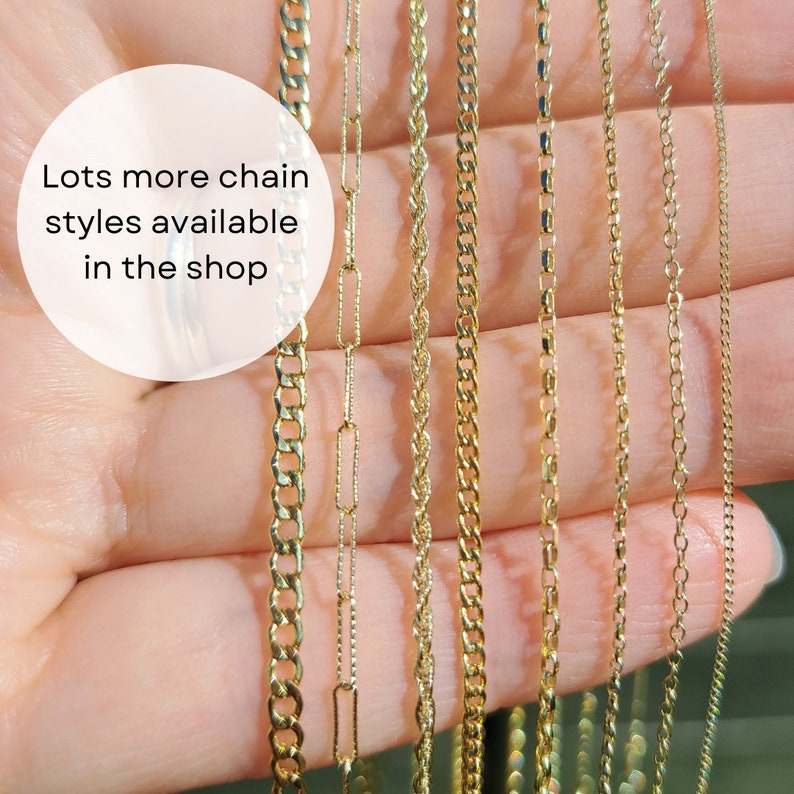 May include: A variety of gold-colored chain necklaces are displayed, showcasing different styles. The chains are held in a hand, with a white circle containing the text "Lots more chain styles available in the shop".