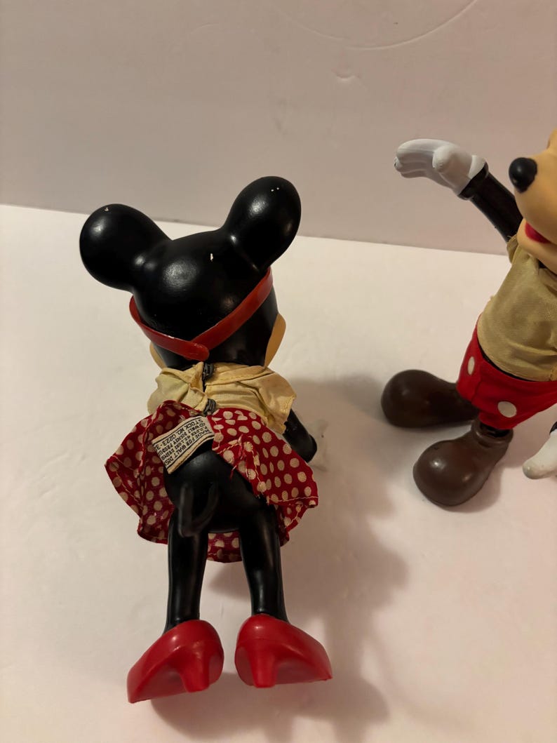 May include: Vintage Minnie Mouse figurine, black with a red polka dot skirt, red shoes, and a red headband. The figurine is wearing a yellow top. Mickey Mouse is also visible in the image.