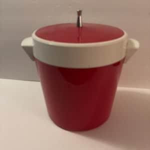 May include: A red and white ice bucket with a lid and handle. The bucket is cylindrical with a red body and a white band around the top. The lid is red with a silver handle.