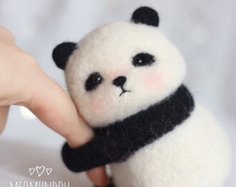 May include: A small, white and black panda bear plush toy with black eyes and a black nose. The panda is holding its arms up and has a black band around its belly.