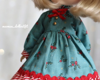 May include: A teal blue dress with a red and white striped ruffle hem. The dress has a red bow at the neck and a holly leaf pattern.