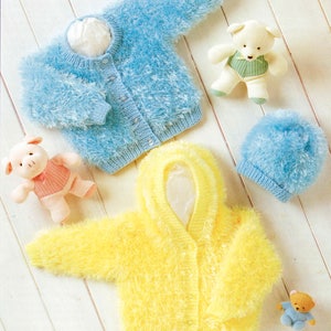 Op de afbeelding: Een lichtblauw en geel fluffy gebreid babyvestje en een bijpassende blauwe muts. De vesten hebben knoopsluitingen. De afbeelding bevat ook knuffels, waaronder een varken, een teddybeer en een witte beer.