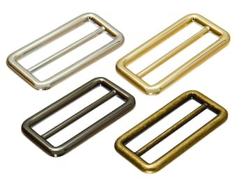 May include: Four metal slider buckles in different finishes: silver, gold, black, and antique brass. Each buckle has a rectangular shape with a smooth, polished surface.