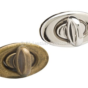 May include: Two oval-shaped metal clasps, one in antique brass and one in silver. Both clasps have a raised oval in the centre.