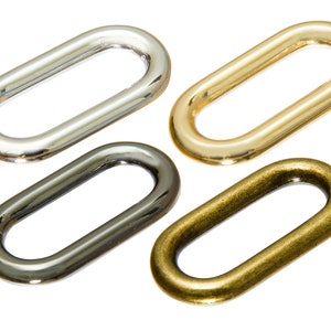 May include: Four oval-shaped metal rings in different finishes: silver, gold, black, and brass.