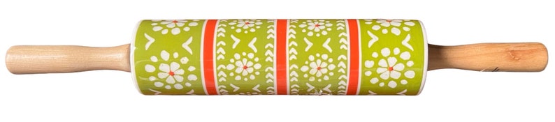 May include: A rolling pin with wooden handles and a patterned center. The center features a green background with white floral and arrow designs, accented by red stripes. A kitchen tool for baking.